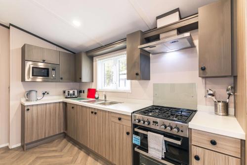 a kitchen with wooden cabinets and a stove top oven at Bushmills Lodge with Hot Tub in Thornton