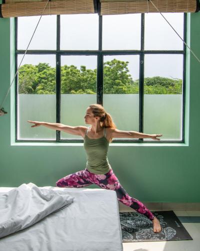 a woman doing yoga on a bed in front of a window at Minimalist One Hauz Khas Village in New Delhi