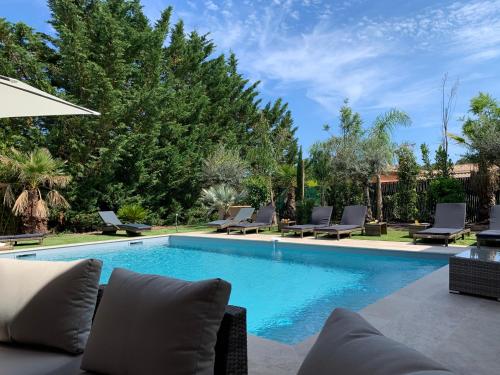 une piscine avec des chaises longues et des chaises tout autour dans l'établissement Villa Giovanna à Saint-Raphaël avec piscine chauffée, à Saint-Raphaël