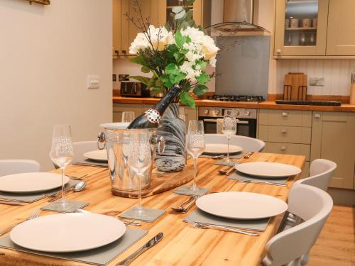 a wooden table with white plates and a vase of flowers at 1 Orchard View in Hathersage