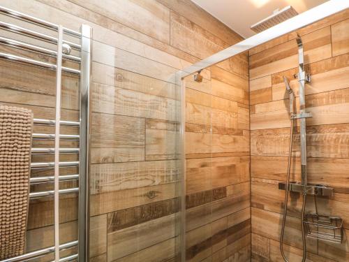a bathroom with a shower with wooden walls at 1 Orchard View in Hathersage