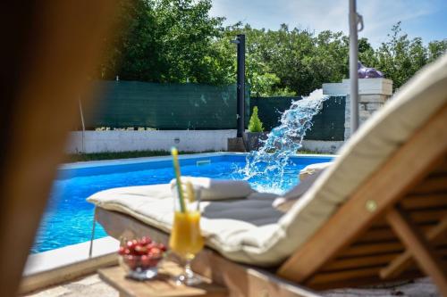 a swimming pool with a fountain and a chair with a drink at Villa Paradise in Prgomet