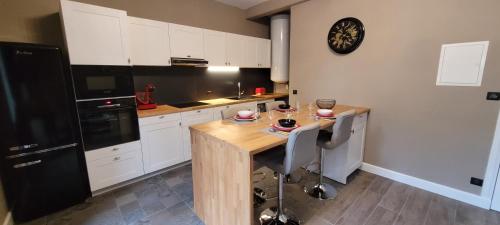 - une cuisine avec une table en bois et un réfrigérateur noir dans l'établissement Appartement Le Moulin Vert, à Carcassonne