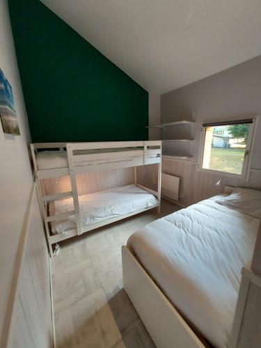 - une chambre avec 2 lits superposés et un mur vert dans l'établissement Les Gîtes du Grand Chêne, à Saint-Paul-en-Born