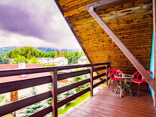 a wooden deck with two chairs and a table on it at Apartamenty Niebo in Kowary