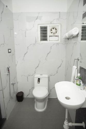 a white bathroom with a toilet and a sink at Hotel Ganesh Palace in Rāmeswaram