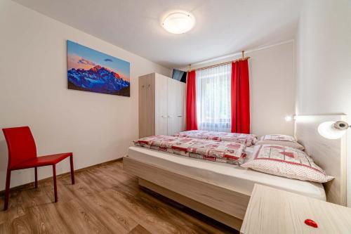 een slaapkamer met een bed en een rode stoel bij Ciesa Sirio in Rocca Pietore