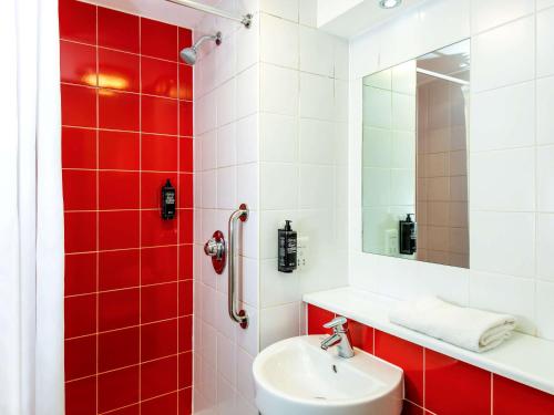 een rood-witte badkamer met een wastafel en een spiegel bij ibis budget Burton Upon Trent Central in Burton upon Trent