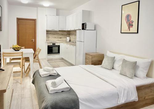 a white bedroom with a large bed and a kitchen at Cozy Studio next to State Opera with Work Space in Stara Zagora