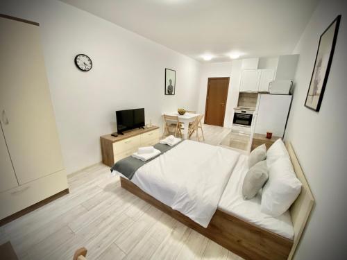 a bedroom with a large white bed and a kitchen at Cozy Studio next to State Opera with Work Space in Stara Zagora