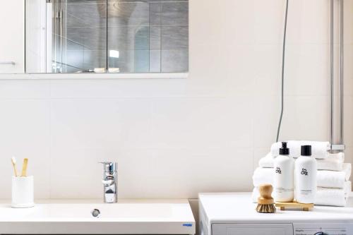 a white bathroom with a sink and a mirror at Tilava kolmio ydinkeskustassa in Oulu