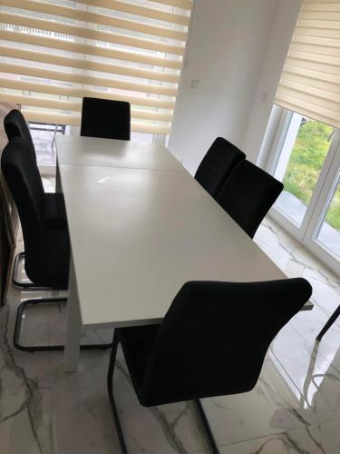 einen weißen Tisch mit schwarzen Stühlen in einem Zimmer in der Unterkunft Luxusvilla Neubau 2 in Oberasbach