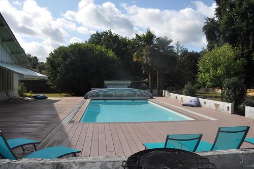 une piscine avec des chaises bleues et une maison dans l'établissement Les Gîtes du Grand Chêne, à Saint-Paul-en-Born
