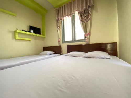 a bedroom with two beds and a window at Homestay Srikandi Syariah Dieng RedPartner in Dieng