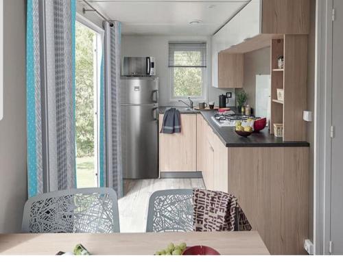 a kitchen with a refrigerator and a table with chairs at Les mobilhomes helvétiques 4 étoiles Mar Estang Canet en Roussillon in Canet-en-Roussillon