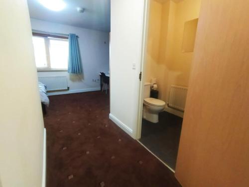 a small bathroom with a toilet and a window at Bankwell Guest House in Manchester