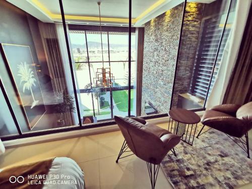 a living room with chairs and a large window at G R A N D C H A L E T in Salalah