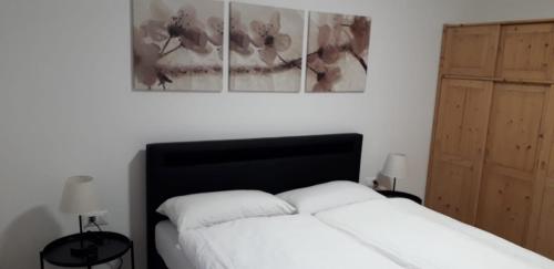 een slaapkamer met een wit bed met drie foto's aan de muur bij Apartment Hagen in Merano