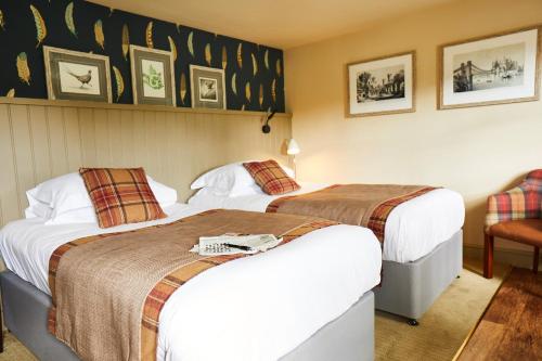 a hotel room with two beds and a chair at The Groes Inn in Conwy