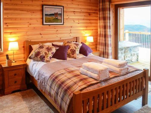 um quarto com uma cama num chalé de madeira em Red Kite & Osprey Lodges em Rhilochan