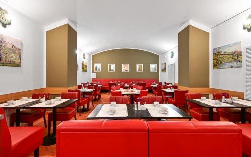 a restaurant with red tables and red chairs at Hotel Malá Strana in Prague