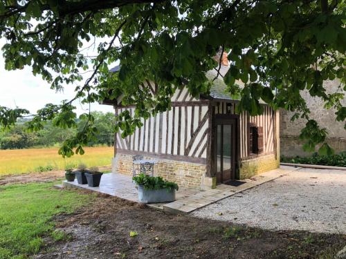 un pequeño edificio de piedra con una puerta en un campo en La Bouillerie du Manoir des Bréholles, en Goustranville