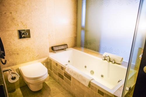 a bathroom with a tub and a toilet and a shower at The Boma Nairobi in Nairobi