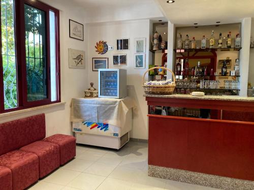 a bar in a restaurant with a red couch and a counter at Hotel Villa Sorci in Rimini