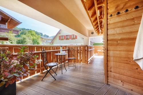 a porch with chairs and tables on a wooden deck at Königshof Hotel Resort in Oberstaufen