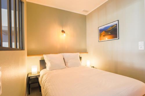 - une chambre avec un grand lit blanc et deux lampes dans l'établissement "Petit Royal" Confort Thermes, à Royat