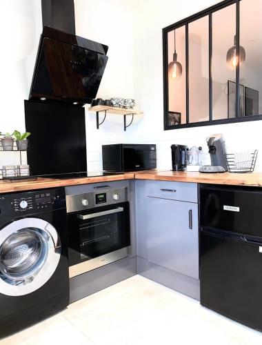 une cuisine équipée d'un lave-linge et d'un lave-linge/sèche-linge. dans l'établissement Jungle garage privé netflix, à Saint-Étienne