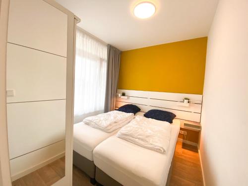 een slaapkamer met 2 bedden en een gele muur bij Vakantieappartement Westkapelle WE07 in Westkapelle