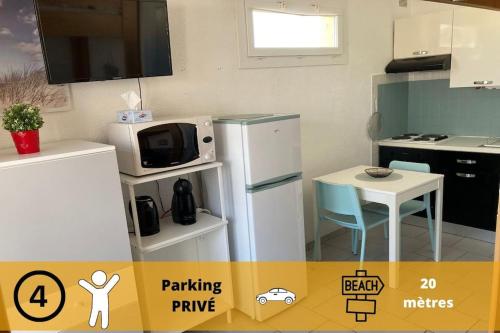 La cuisine est équipée d'un réfrigérateur, d'une table et d'un four micro-ondes. dans l'établissement Le BARCA Playa - Climatisé - Terrasse et Parking privé, au Barcarès