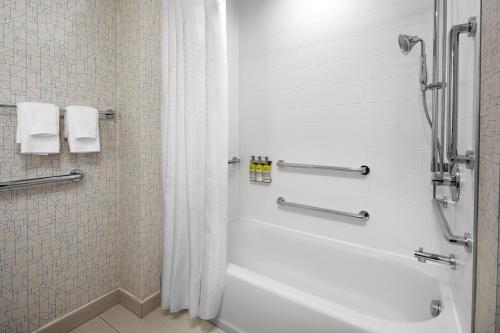 a bathroom with a white tub and a shower at Holiday Inn Express & Suites Woodside LaGuardia Airport in Queens