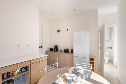 une cuisine avec une table et un réfrigérateur blanc dans l'établissement La Dame de la Mer - en plein cœur de Dinard, à Dinard