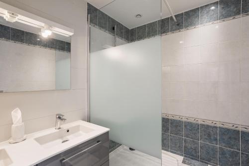 a bathroom with a sink and a shower with a mirror at La Dame de la Mer - en plein cœur de Dinard in Dinard