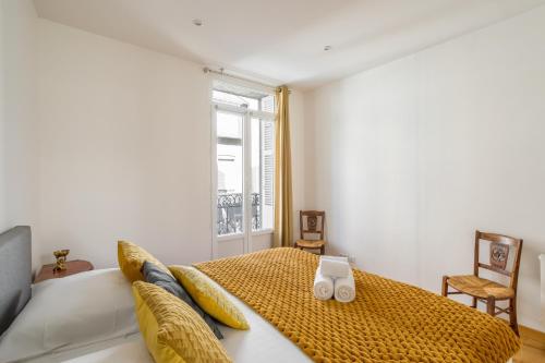 a bedroom with a bed with yellow pillows and a window at La Dame de la Mer - en plein cœur de Dinard in Dinard