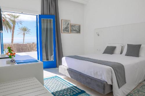 a bedroom with a bed and a view of the ocean at Hari Club Beach Resort in Aghīr