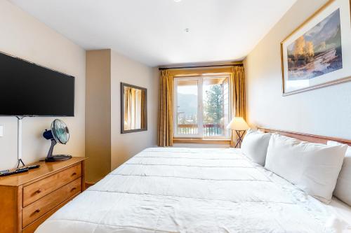 a bedroom with a large white bed with a flat screen tv at Juniper Springs 444 in Mammoth Lakes
