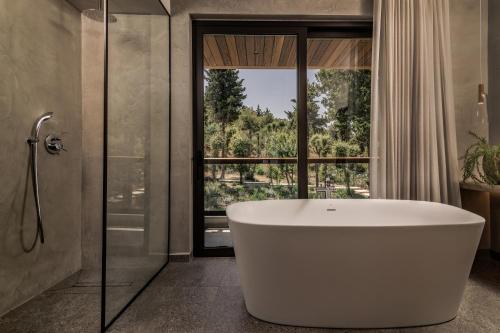 a bath tub in a bathroom with a large window at Sentiero Iconic Villa, a Serene Retreat, By ThinkVilla in Plános