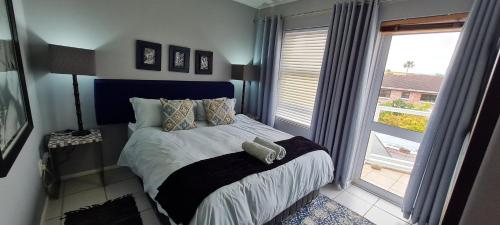 a bedroom with a bed with a large window at Knysna Sunrise @Malachite in Knysna