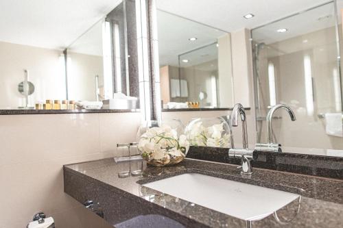 ein Badezimmer mit einem Waschbecken und einem großen Spiegel in der Unterkunft PLAZA Hotel Gelsenkirchen in Gelsenkirchen