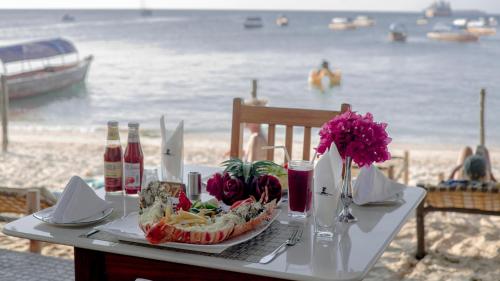 a table with a plate of food on the beach at Tembo House Hotel in Zanzibar City
