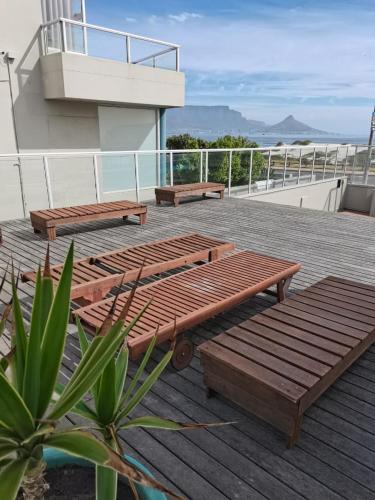 a deck with two benches on top of a building at On The Beach Front Sea Spray in Bloubergstrand