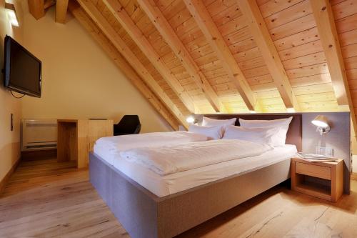 1 dormitorio con 1 cama grande y techo de madera en HOTEL WIENER BOTSCHAFT Veitshöchheim - by homekeepers, en Veitshöchheim