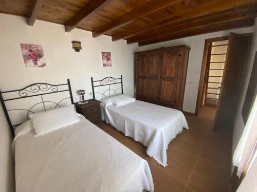 1 dormitorio con 2 camas y puerta de madera en Pajero Las Cadenas, en Valverde