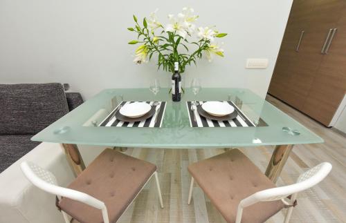 a glass table with a vase of flowers on it at Royal Accommodation in Bucharest