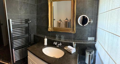 une salle de bain avec un lavabo et un miroir dans l'établissement Le Couvent, à Saint-Jean-de Laurs