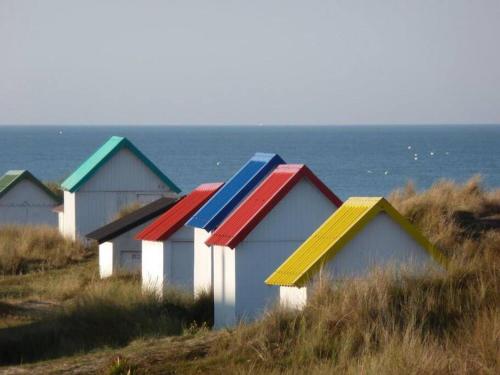 a row of colorful houses on a hill near the ocean at Villa des Dunes in Gouville-sur-Mer