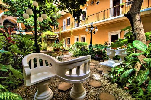un jardin avec un banc blanc devant un bâtiment dans l'établissement Hotel Caribe Merida Yucatan, à Mérida